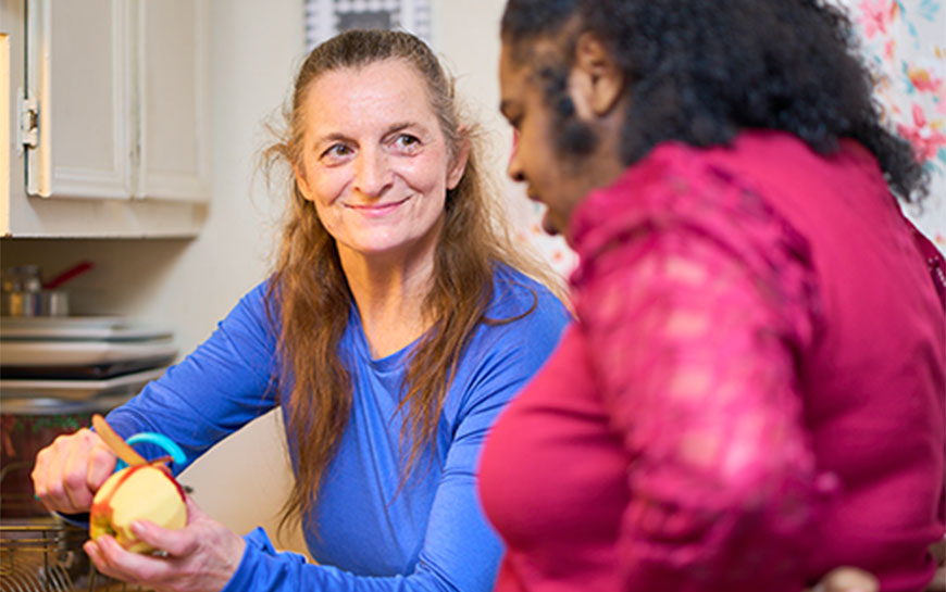 Care worker peeling an apple for another woman