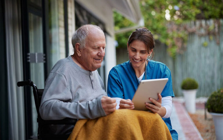 Caregiver and elderly man looking at tablet