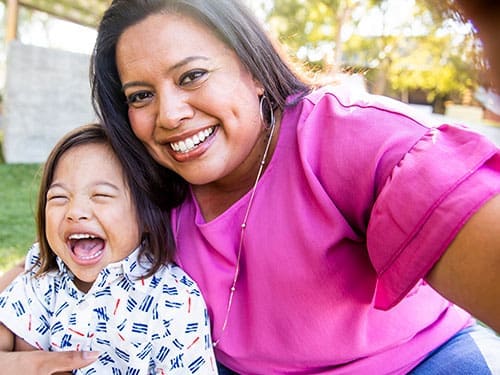 A Carewell benefit recipient and her child taking a selfie outside