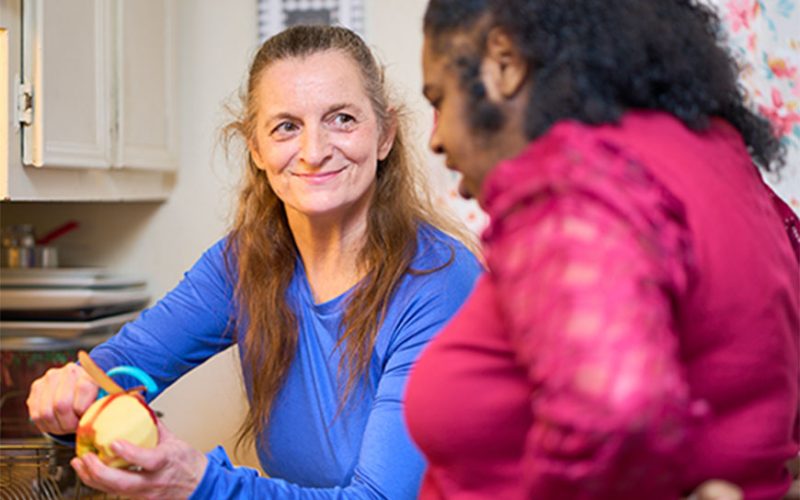 Care worker peeling an apple for another woman